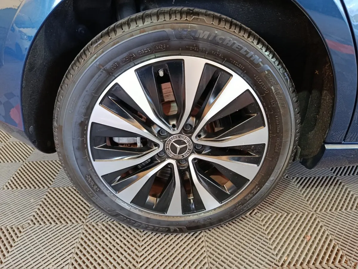 Gros plan sur la roue avant droite d’une Mercedes Classe A bleu, jante alliage noir et argentée design moderne.