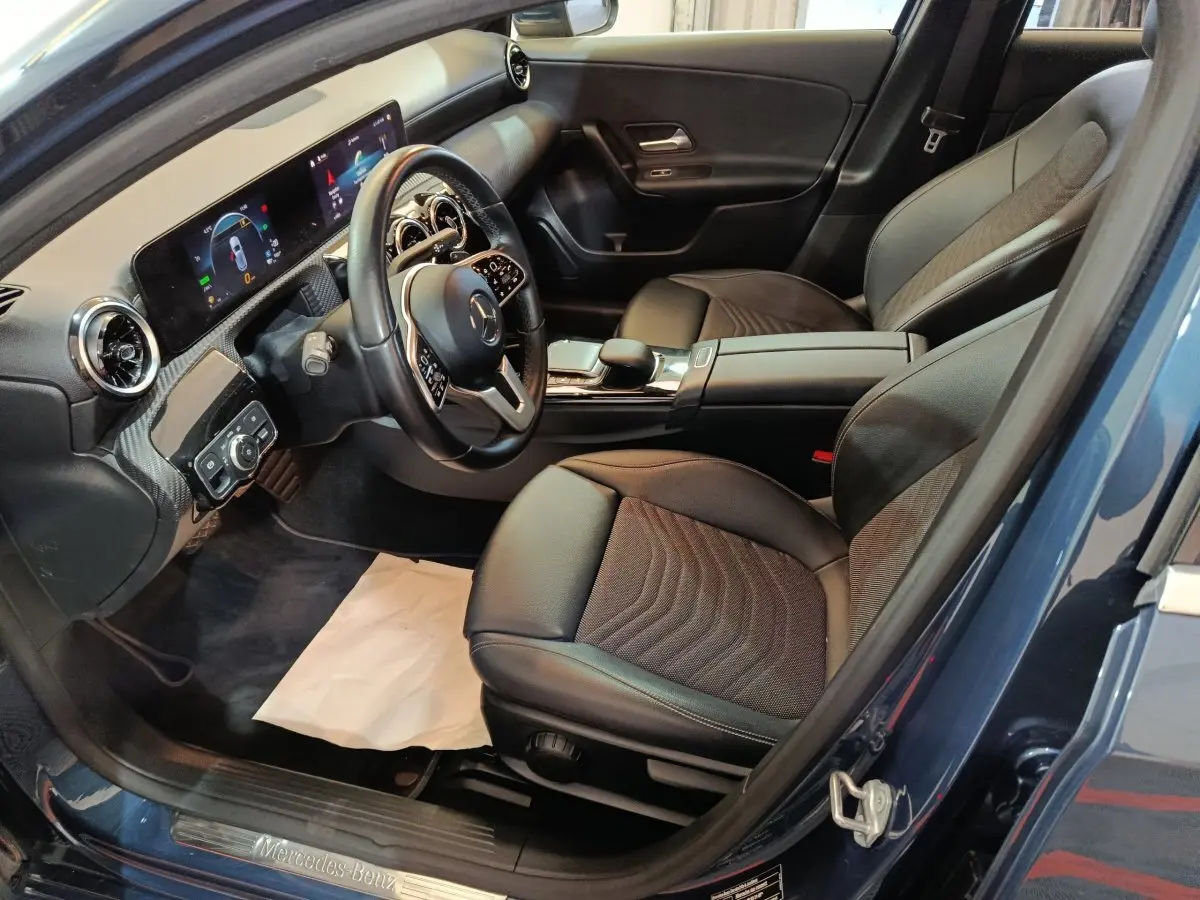 Vue intérieure côté conducteur de la Mercedes Classe A 250 e Business Line bleu, volant cuir et écran tactile visible.