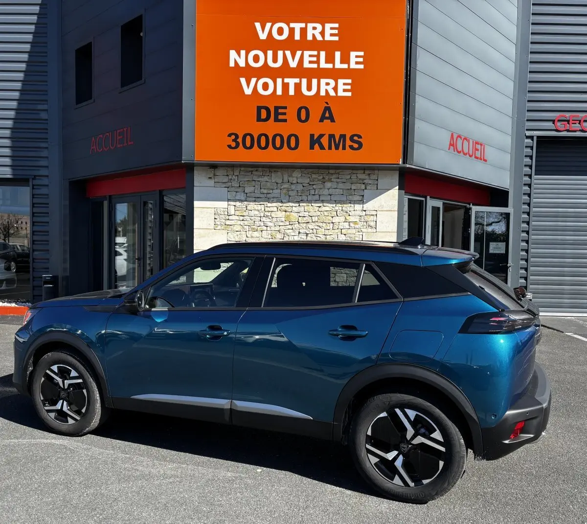 Vue de profil côté gauche d’un Peugeot 2008 Hybrid 145 bleu 2025 avec toit noir et jantes distinctives.