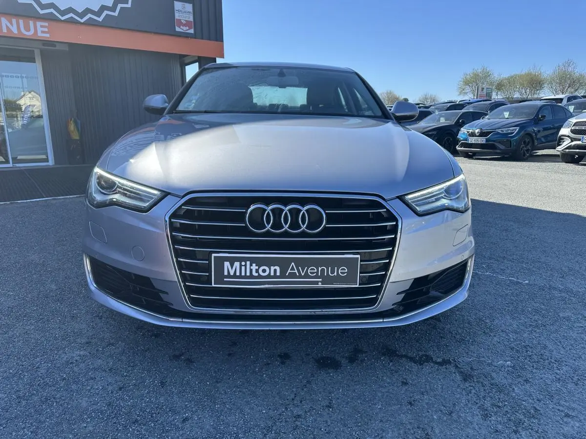 Vue avant d'une Audi A6 gris métallisé avec calandre Singleframe chromée et phares LED, stationnée en extérieur.