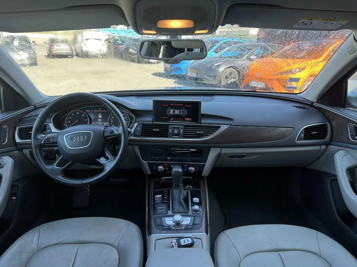 Vue intérieure avant de l'Audi A6 2015 avec tableau de bord et volant multifonction en cuir gris clair.