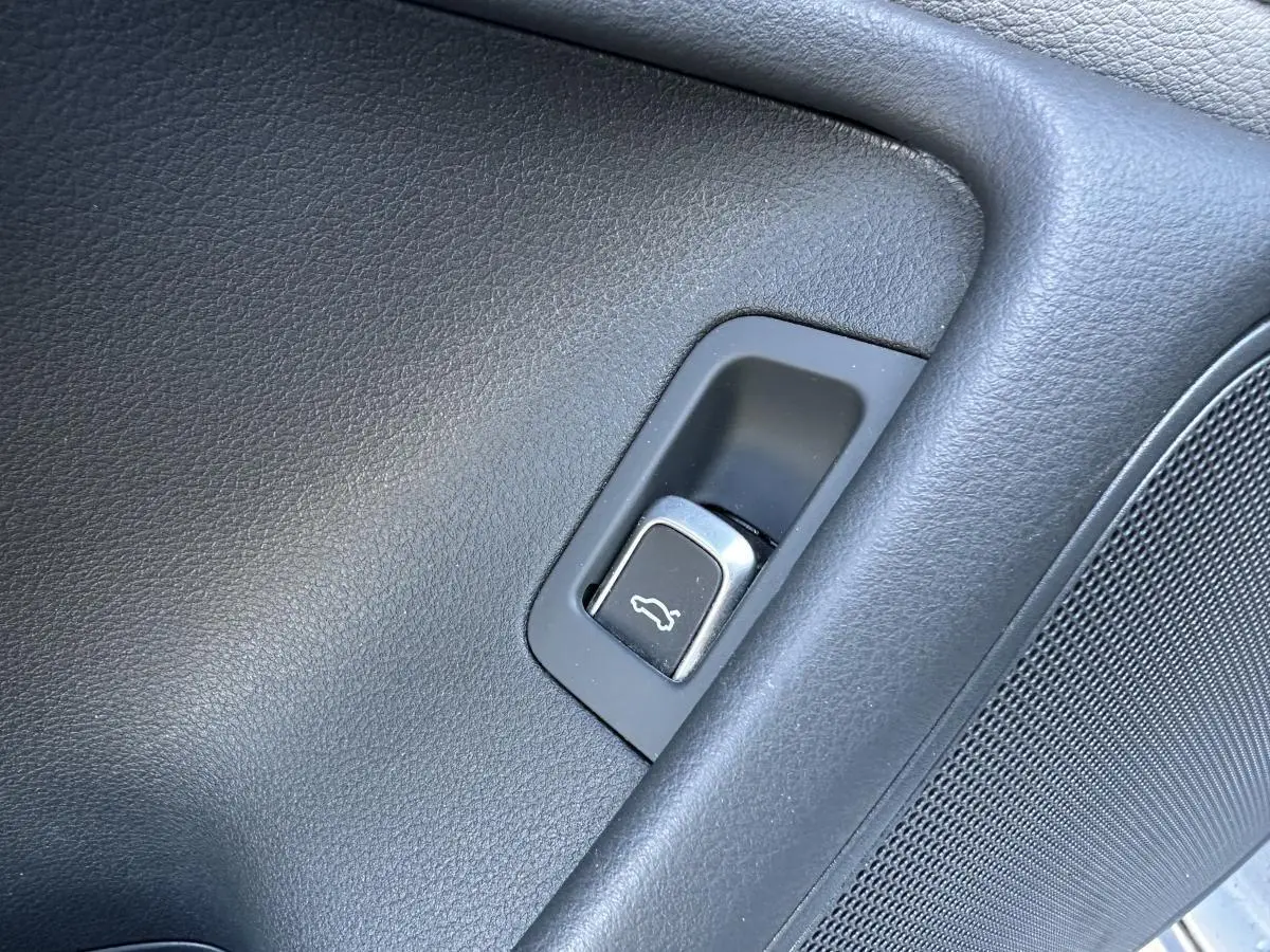 Bouton d'ouverture électrique du hayon sur la porte intérieure côté gauche d'une Audi A6 gris 2015.