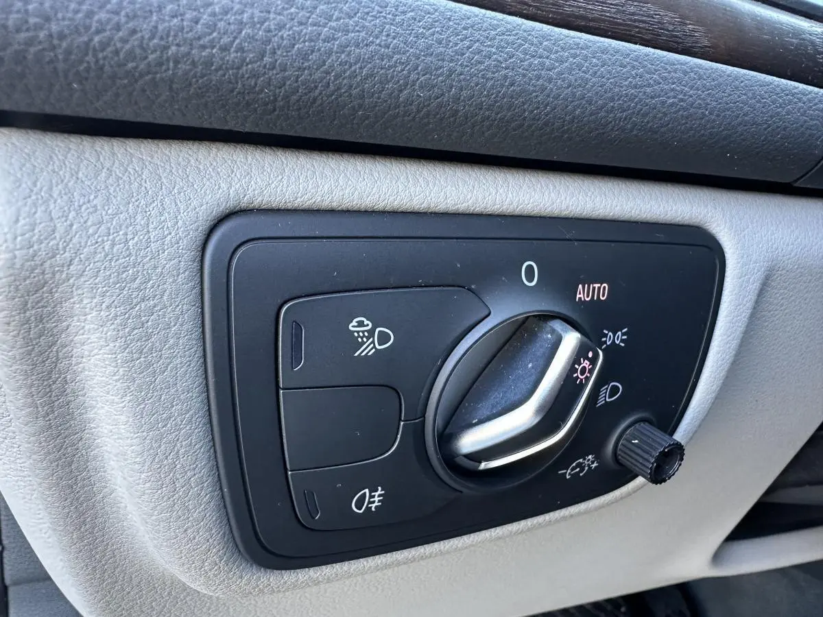 Gros plan sur la commande des phares de l’Audi A6 2015, avec molette en position automatique sur panneau gris clair.