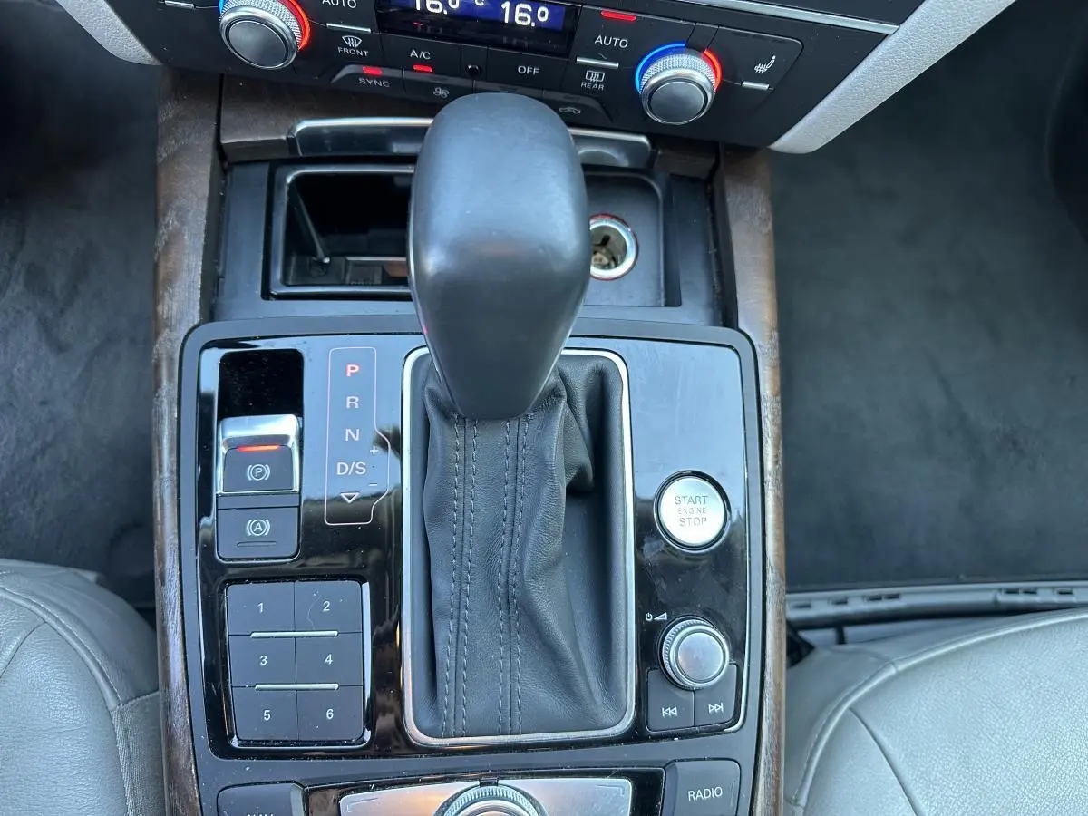 Vue rapprochée de la console centrale de l'Audi A6 2015, montrant levier de vitesses cuir et boutons de commande noirs.