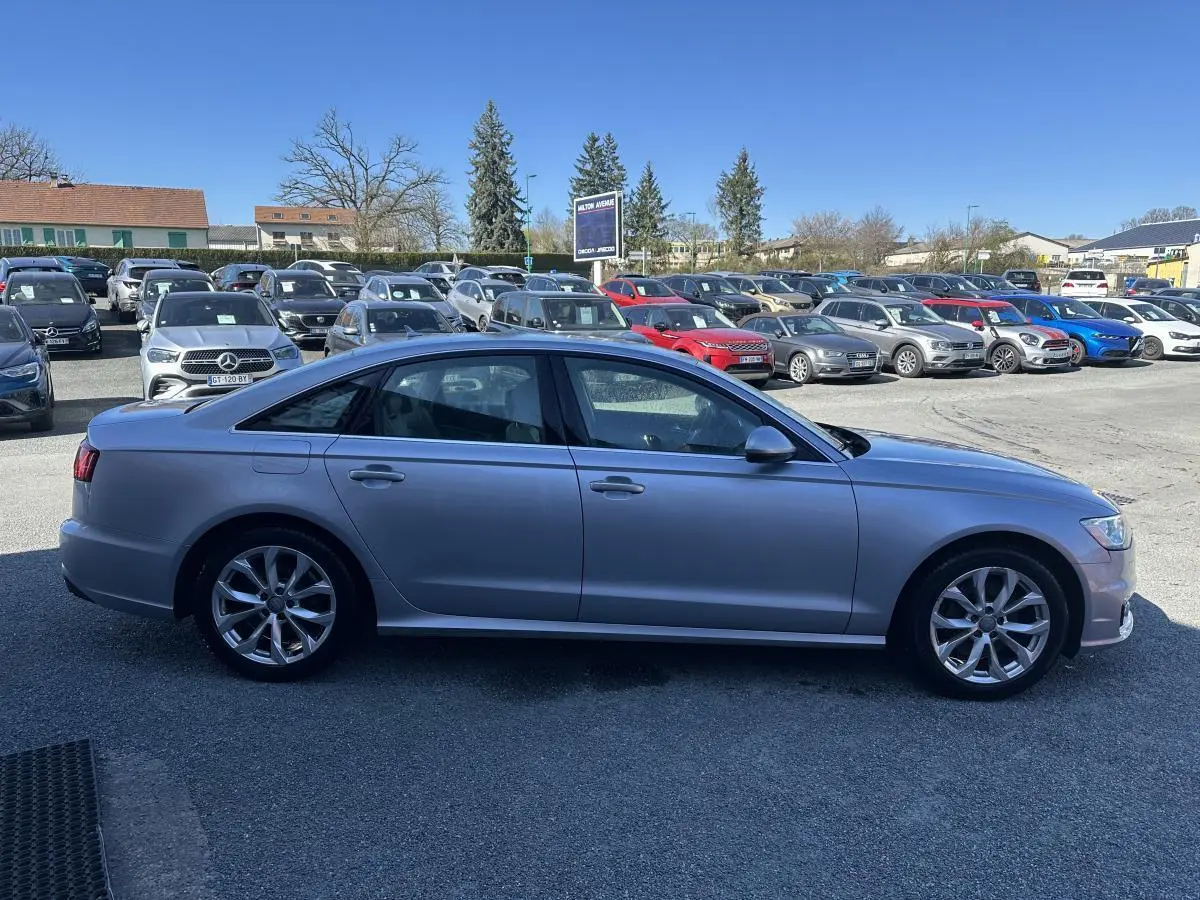 Audi A6 gris vue de profil côté gauche sur un parking en extérieur par temps clair.