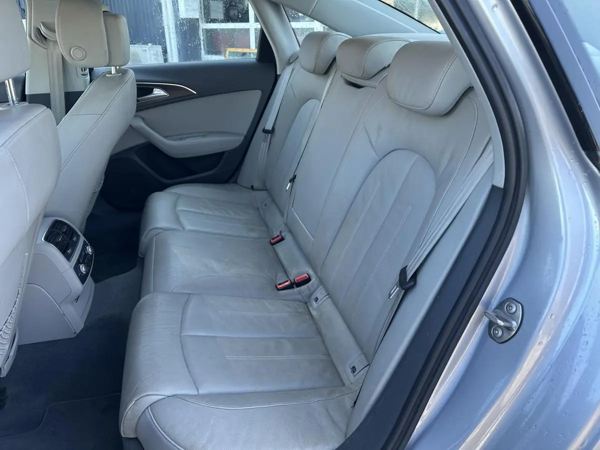 Vue intérieure côté droit montrant la banquette arrière en cuir gris clair de l'Audi A6 2015 avec accoudoirs et aérateurs centraux.