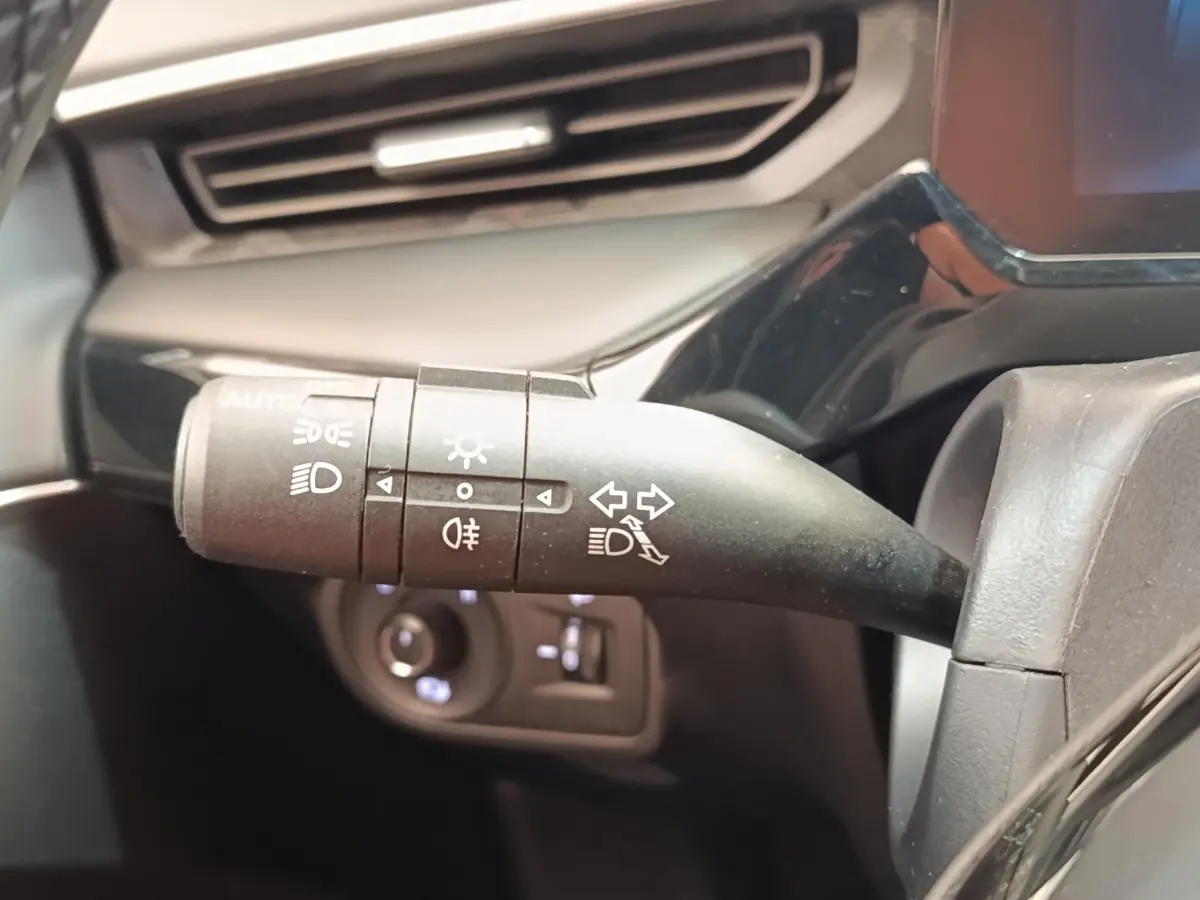 Gros plan sur la commande des phares et clignotants du MG3 1.5L Hybrid+ Luxury, intérieur noir et gris.