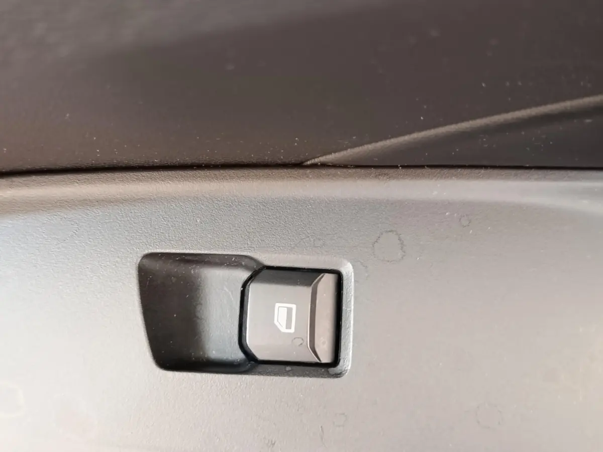 Gros plan sur le bouton de commande de lève-vitre intérieur, plastique noir, dans une MG3 2024 gris foncé.
