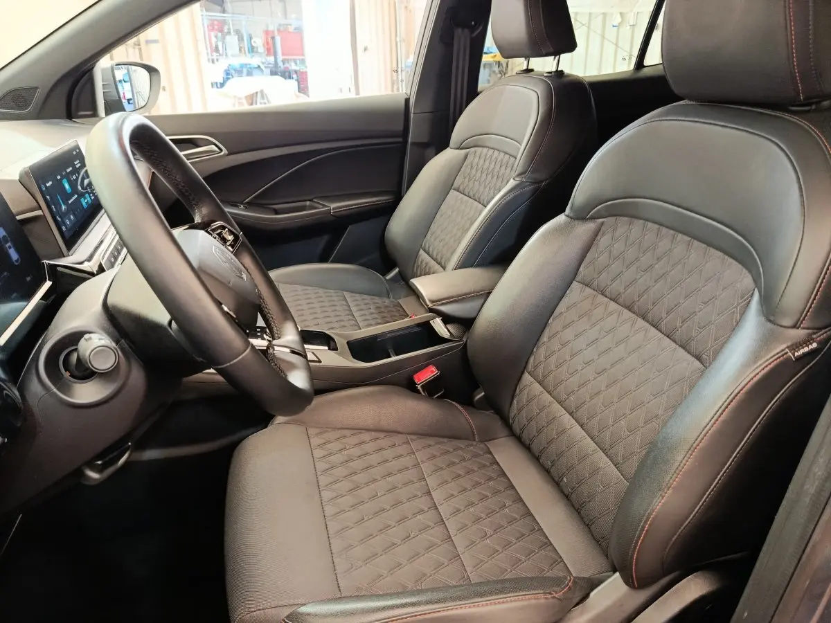 Vue intérieure côté conducteur du MG3 1.5L Hybrid+ Luxury 2024, sièges cuir noir avec surpiqûres rouges et tableau de bord digital.