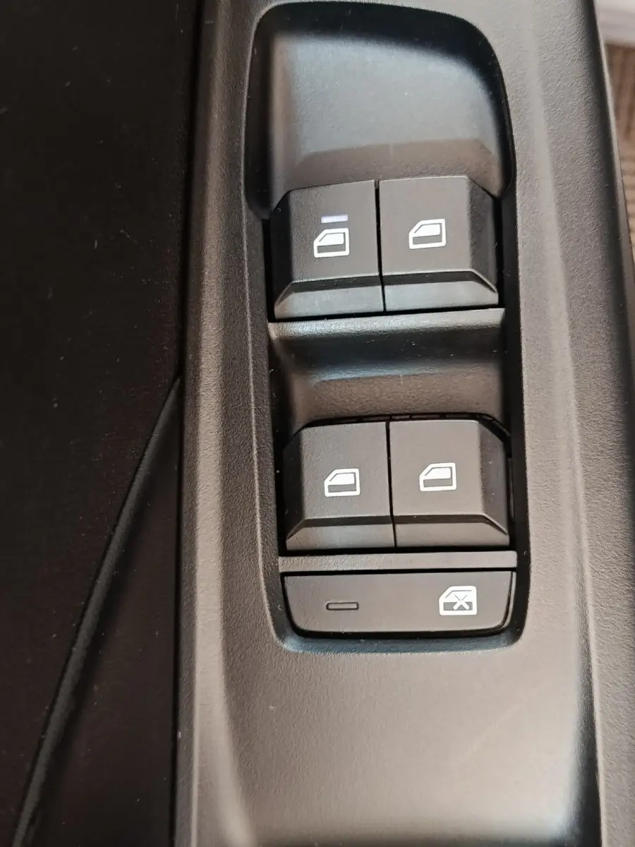 Gros plan sur les commandes de lève-vitres électriques en plastique noir dans l’habitacle du MG3 gris foncé 2024.