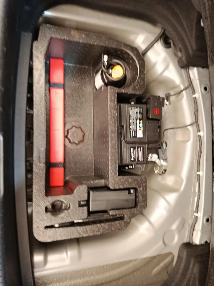 Vue rapprochée du coffre d’un MG3 2024 gris foncé, montrant la batterie et le rangement d’outils intégrés.