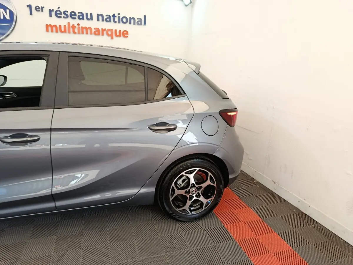 Vue latérale arrière droite d'une MG3 gris foncé avec jante alliage et feu arrière LED visible en intérieur showroom.