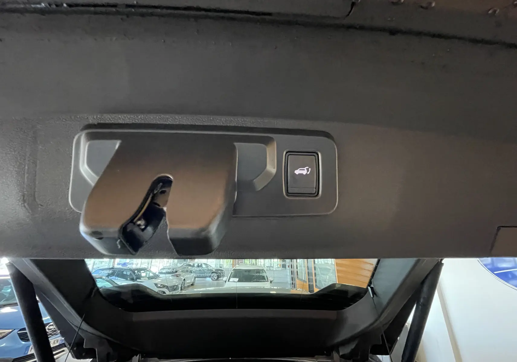 Gros plan sur la serrure et le bouton d'ouverture électrique du coffre du Renault Rafale gris shiste, vue intérieure arrière.