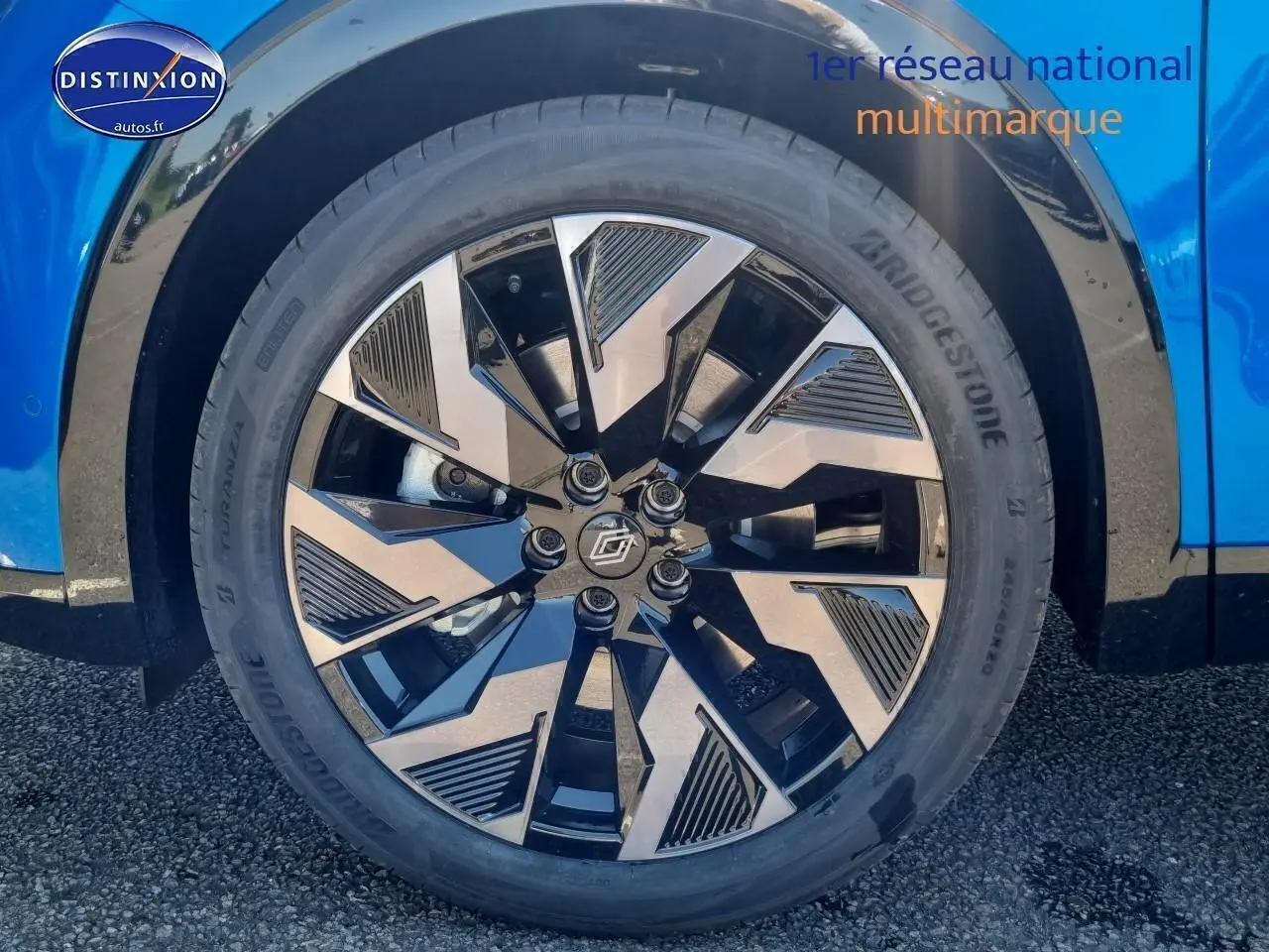 Gros plan sur la jante alu noire et argent du côté avant droit d'une Renault Rafale bleu sommet.