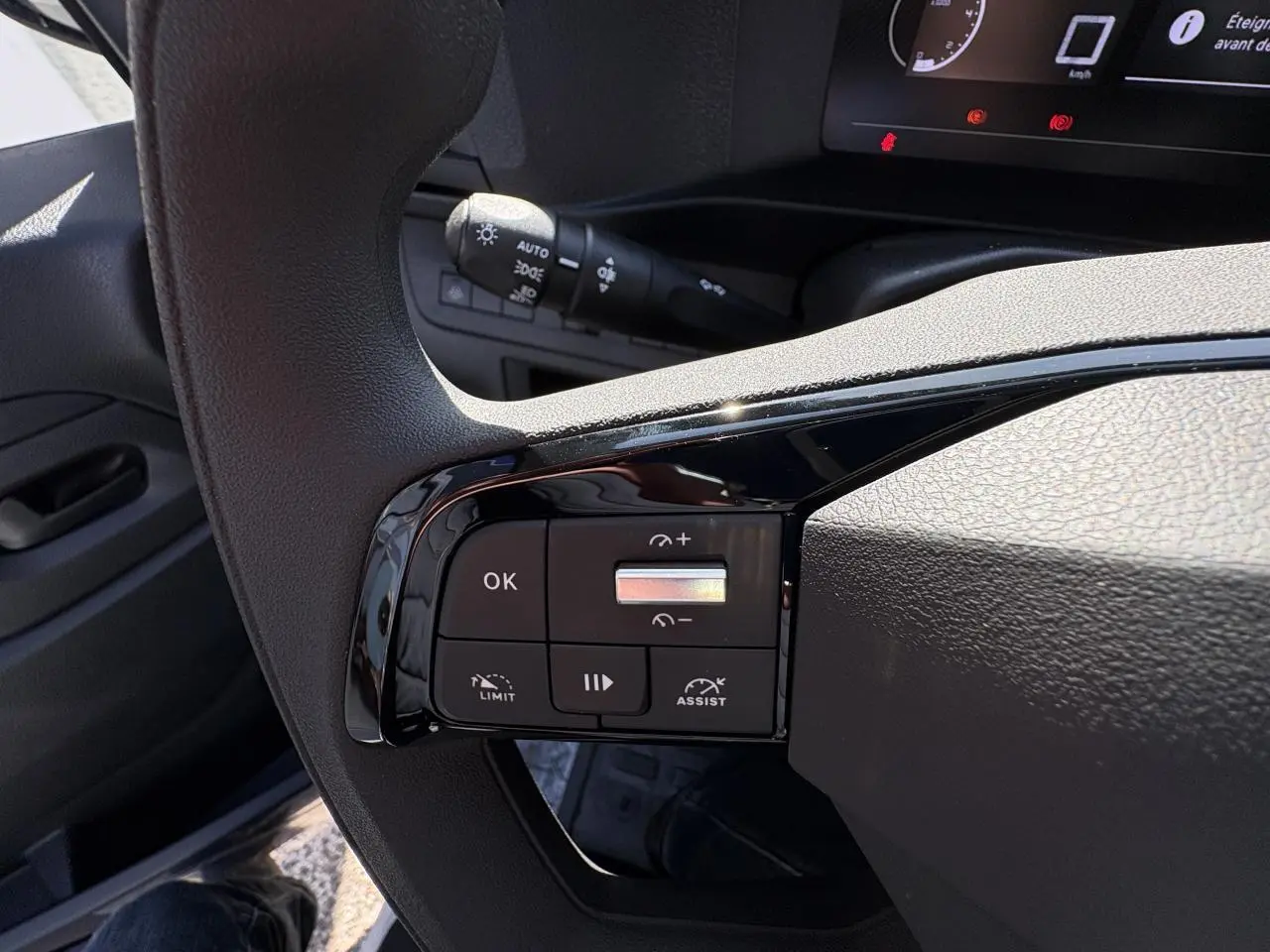 Gros plan sur les commandes au volant à gauche de l’Opel Vivaro blanc, avec tableau de bord numérique en arrière-plan.