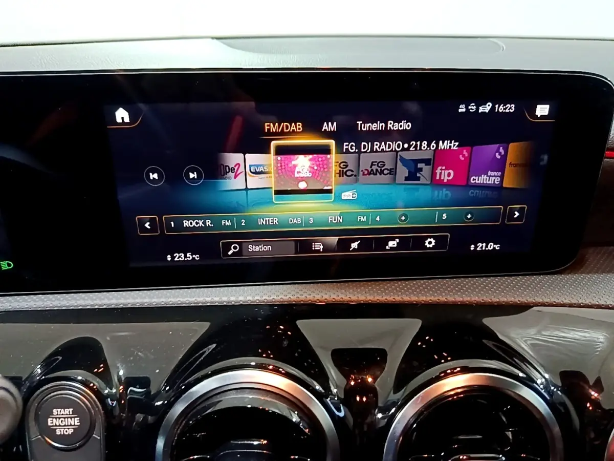 Gros plan sur l’écran tactile central et les aérateurs ronds noirs du tableau de bord de la Mercedes Classe A gris foncé.
