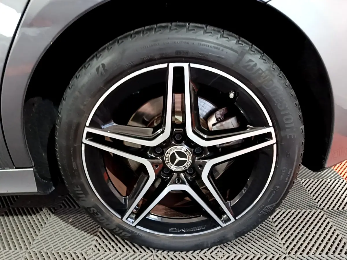 Gros plan sur la jante AMG noire et argent d'une Mercedes Classe A 250 e gris foncé, vue côté gauche.