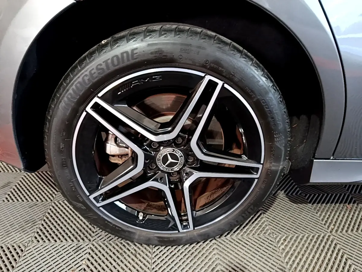 Gros plan sur la roue avant droite de la Mercedes Classe A 250 e AMG Line gris foncé avec jante AMG noire et argent.