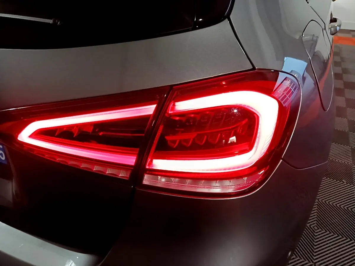 Gros plan sur le feu arrière droit allumé d'une Mercedes Classe A 250 e AMG Line gris foncé, vue arrière partielle.