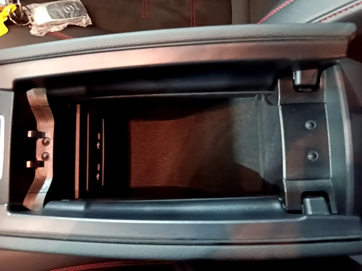 Vue plongeante sur le rangement central noir de la Mercedes Classe A 250 e AMG Line 2021 avec coutures rouges visibles.