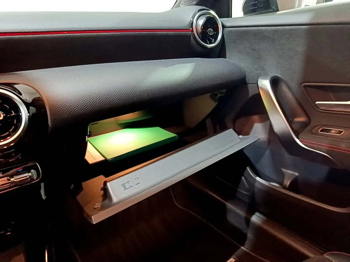 Vue intérieure côté passager du coffre à gants ouvert avec éclairage vert dans la Mercedes Classe A A 250 e AMG Line 2021.
