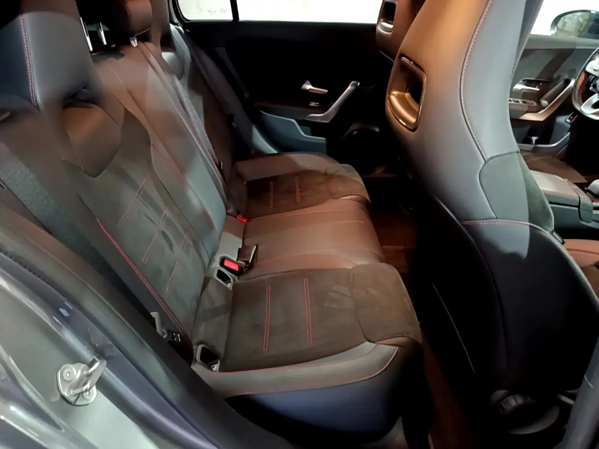 Vue intérieure côté gauche montrant la banquette arrière en cuir et alcantara noir avec surpiqûres rouges d'une Mercedes Classe A A 250 e AMG Line 2021.