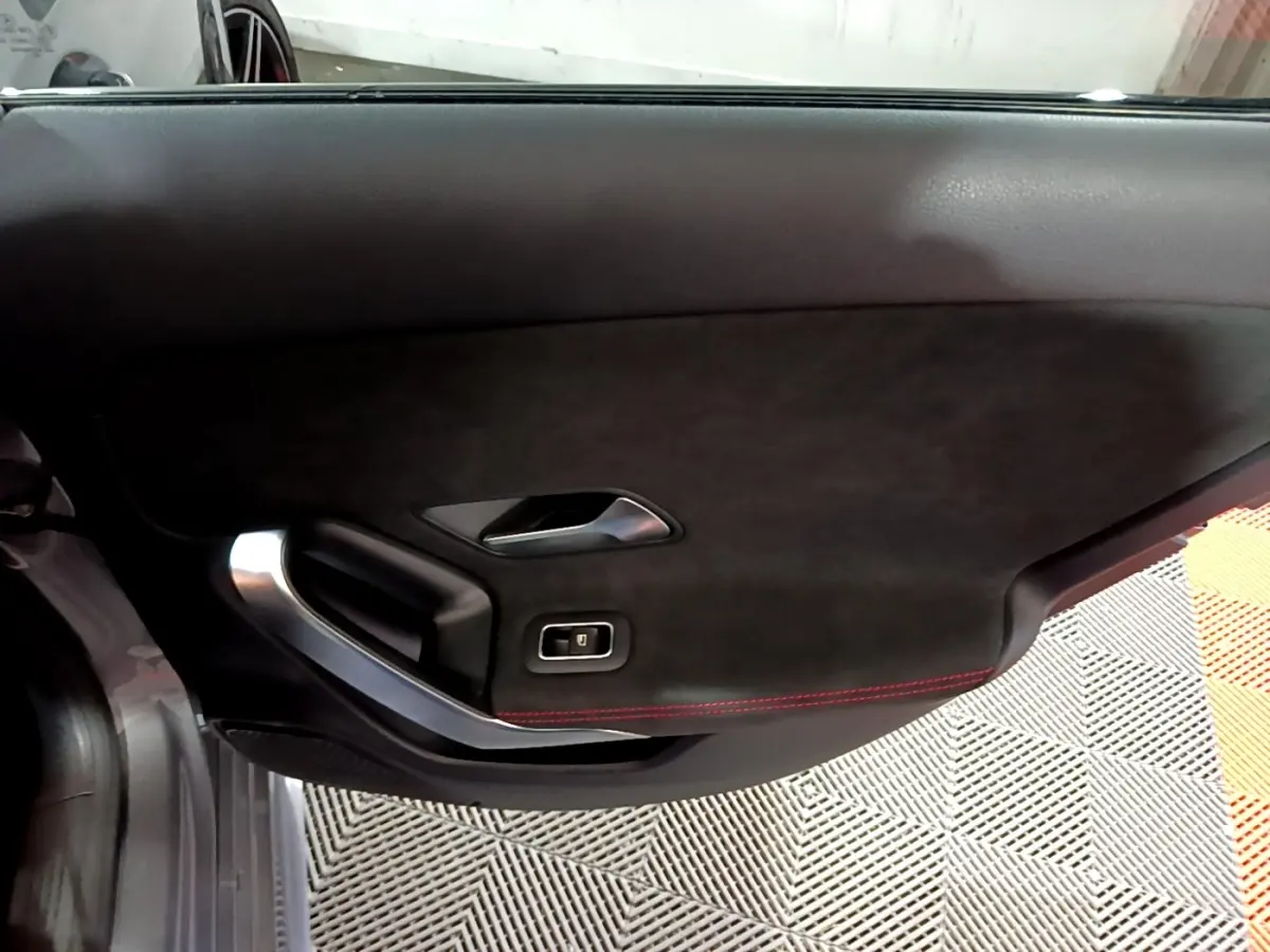 Gros plan sur la porte intérieure côté gauche de la Mercedes Classe A A 250 e AMG Line, avec finition noire et surpiqûres rouges.