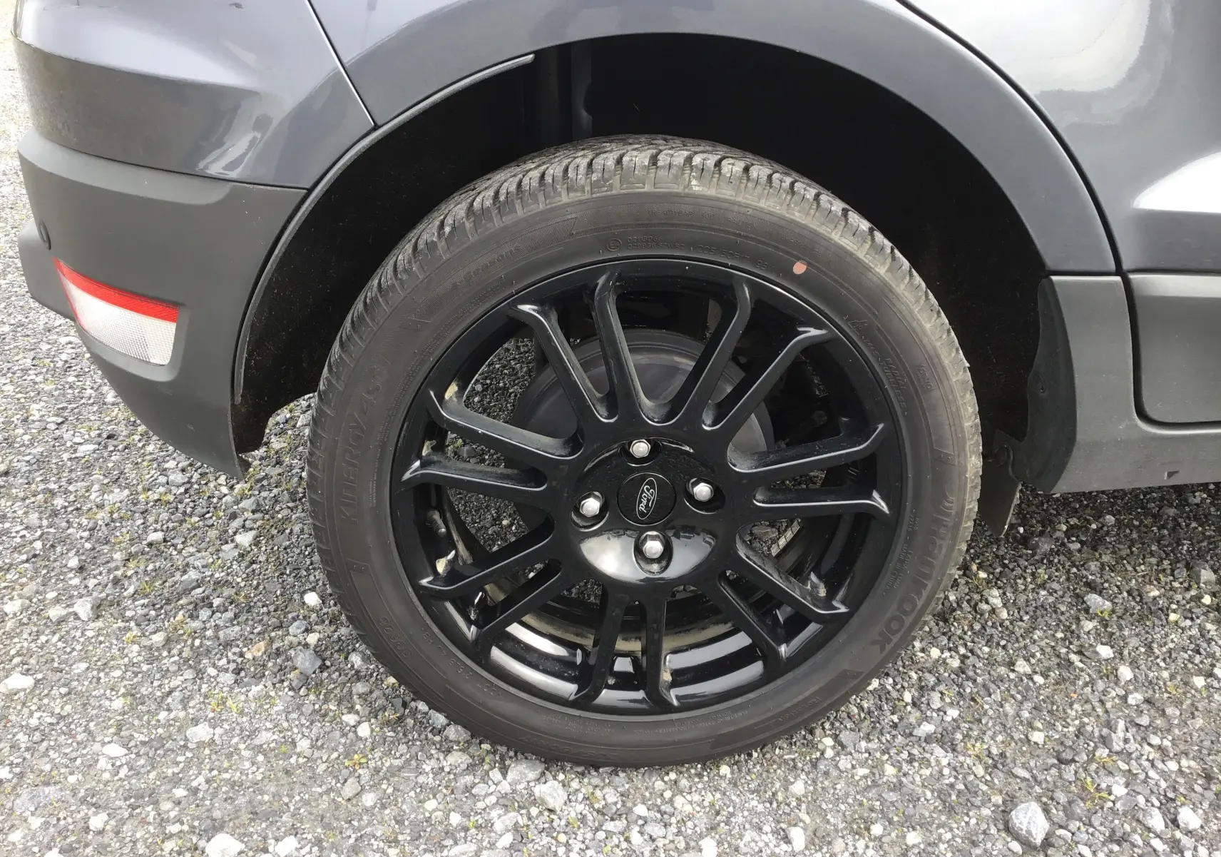 Gros plan sur la roue arrière droite noire brillante du Ford Ecosport gris foncé métallisé de 2017.