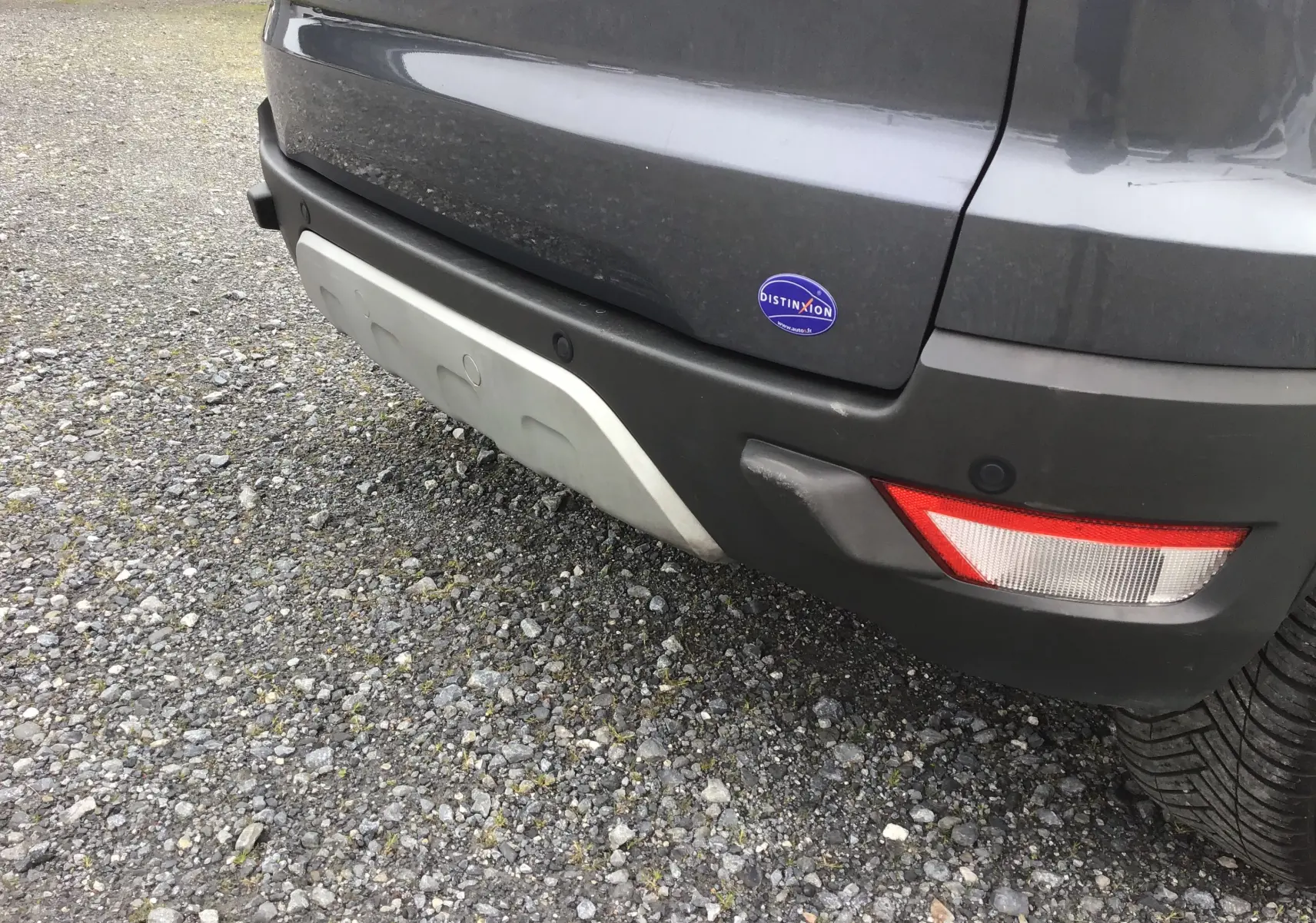Vue rapprochée du pare-chocs arrière droit d’un Ford Ecosport gris foncé avec feu arrière et badge Distinxion.