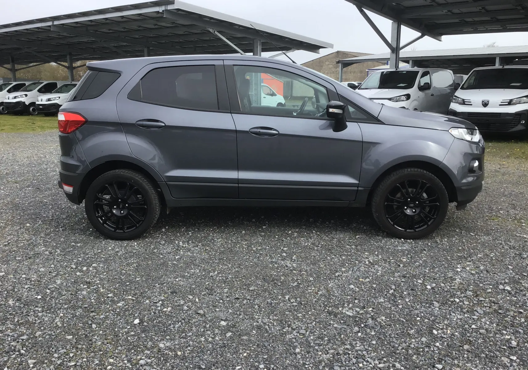 Ford EcoSport gris foncé métallisé vu de profil côté gauche, avec jantes noires et vitres teintées.