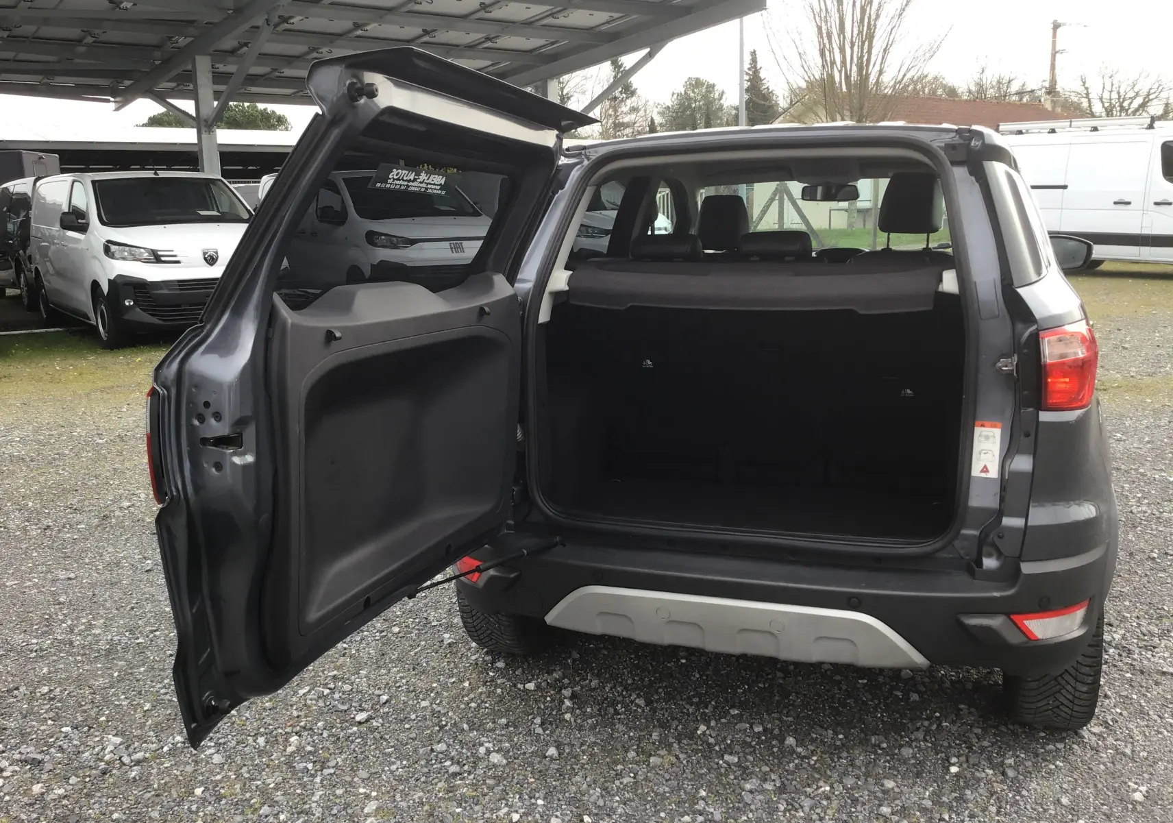 Vue arrière du Ford EcoSport gris foncé métal 2017 avec porte de coffre latérale ouverte montrant l'espace de chargement.