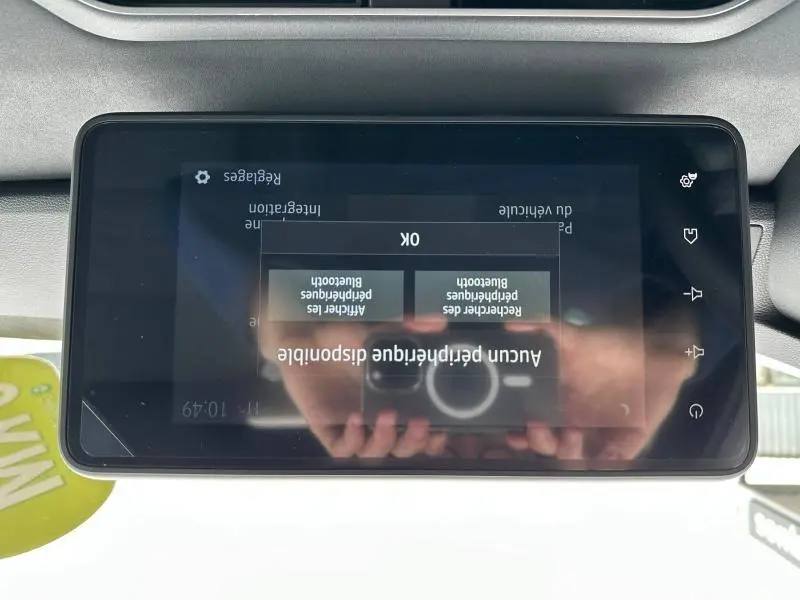 Écran tactile central du tableau de bord du Dacia Jogger 2024, affichant un menu de réglages, avec reflet du photographe.