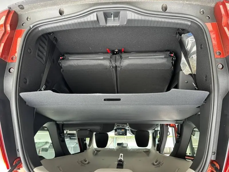 Vue plongeante sur le coffre ouvert du Dacia Jogger brun Terracota, montrant la banquette arrière rabattue et le cache-bagages.