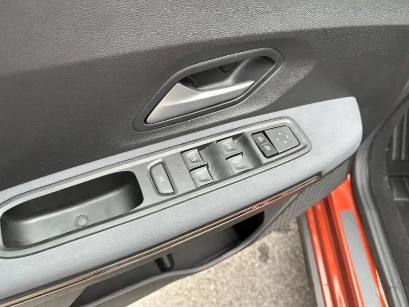 Gros plan sur la porte avant gauche brun Terracota du Dacia Jogger 2024 avec commandes des vitres et rétroviseurs.