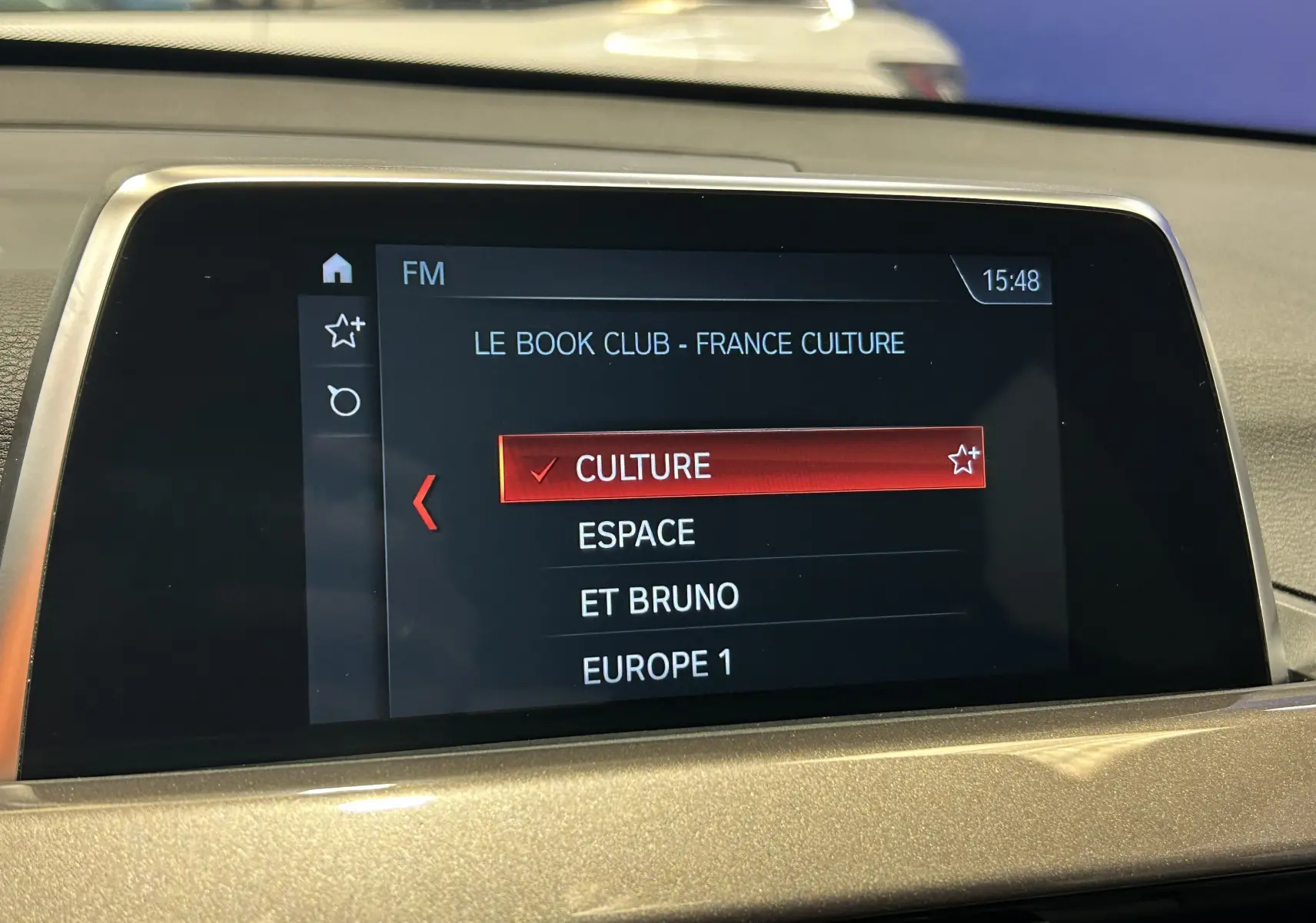 Écran central de la BMW X1 blanc 2018 affichant la sélection radio FM sur le menu "Culture" à 15h48.