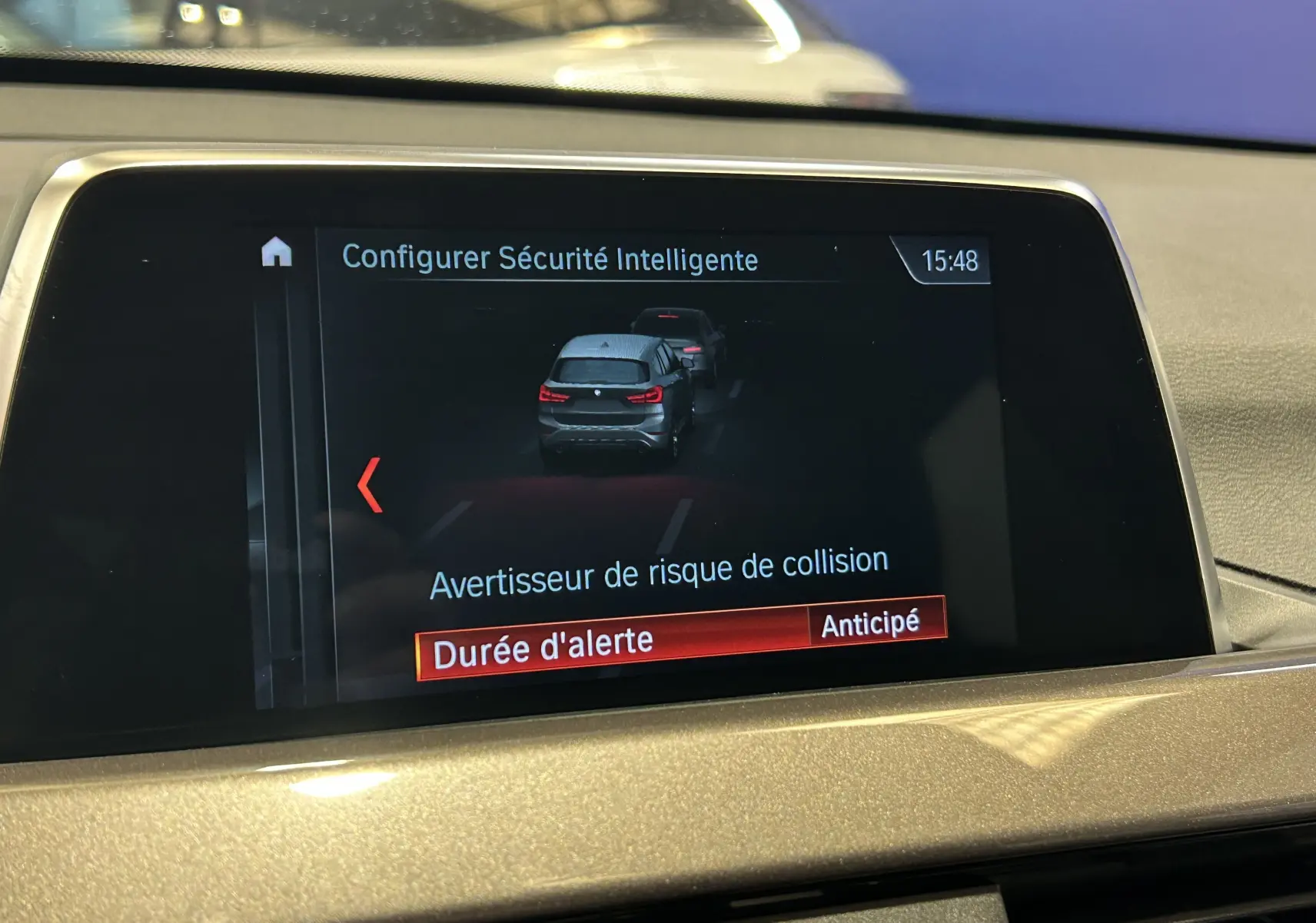 Écran central intérieur montrant la configuration de l'alerte de collision sur BMW X1 blanc, vue de face.