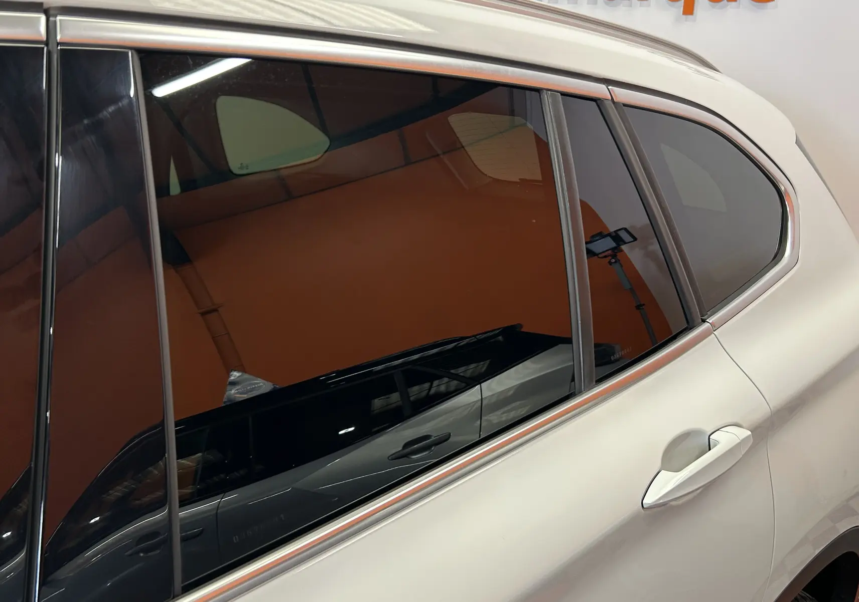 Vue latérale droite sur la porte arrière blanche d’un BMW X1 2018 avec vitres teintées et poignée intégrée.