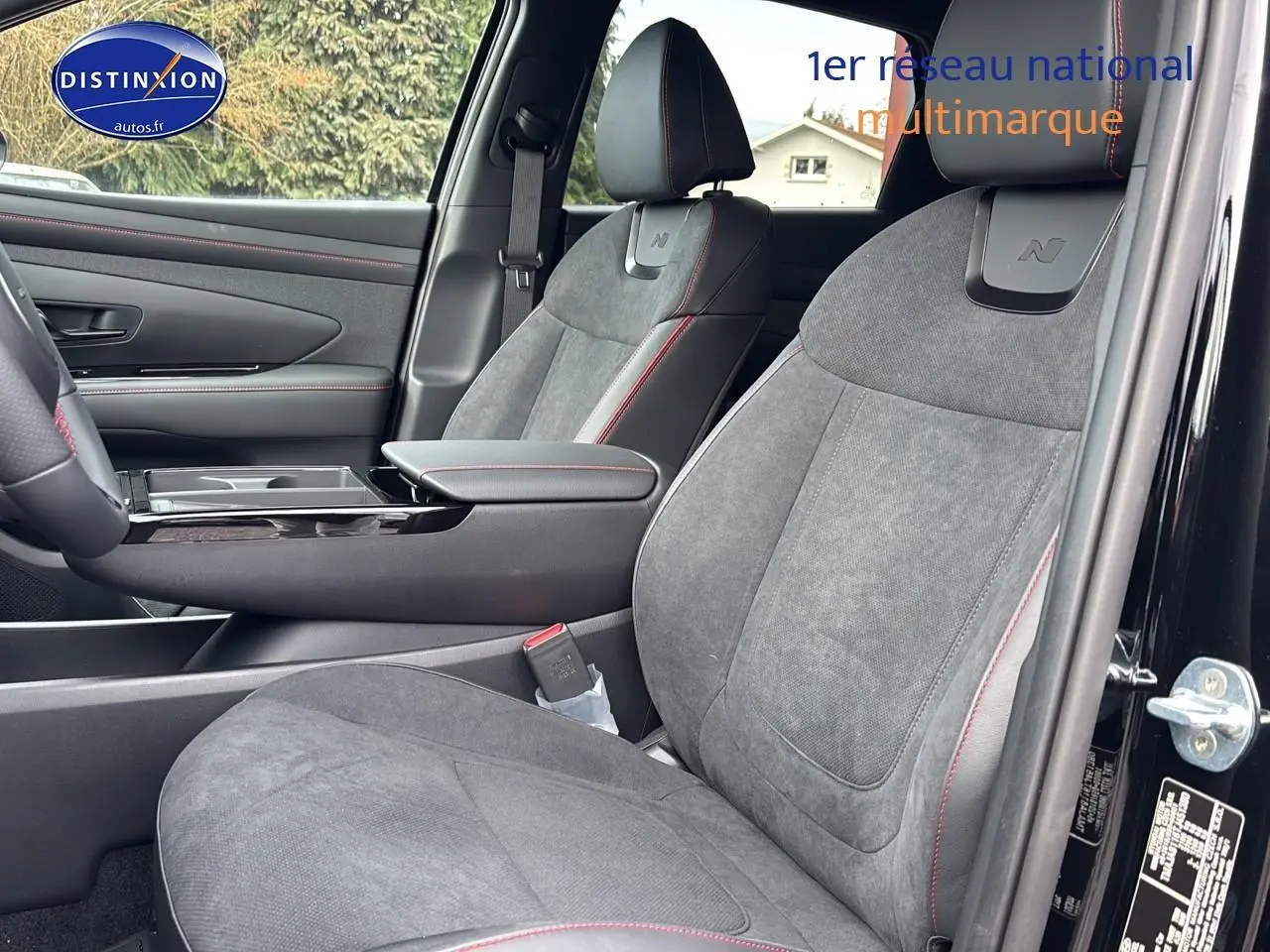 Vue intérieure côté conducteur du Hyundai Tucson 2026 noir, sièges N-line en tissu gris avec surpiqûres rouges.
