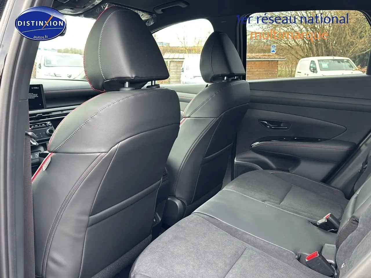 Vue intérieure arrière du Hyundai Tucson 2026 noir, sièges cuir et alcantara avec surpiqûres rouges, ambiance N Line.