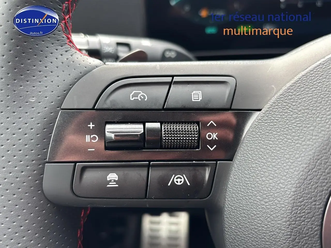 Gros plan sur les commandes multifonctions noires du volant cuir perforé avec surpiqûres rouges du Hyundai Tucson noir.