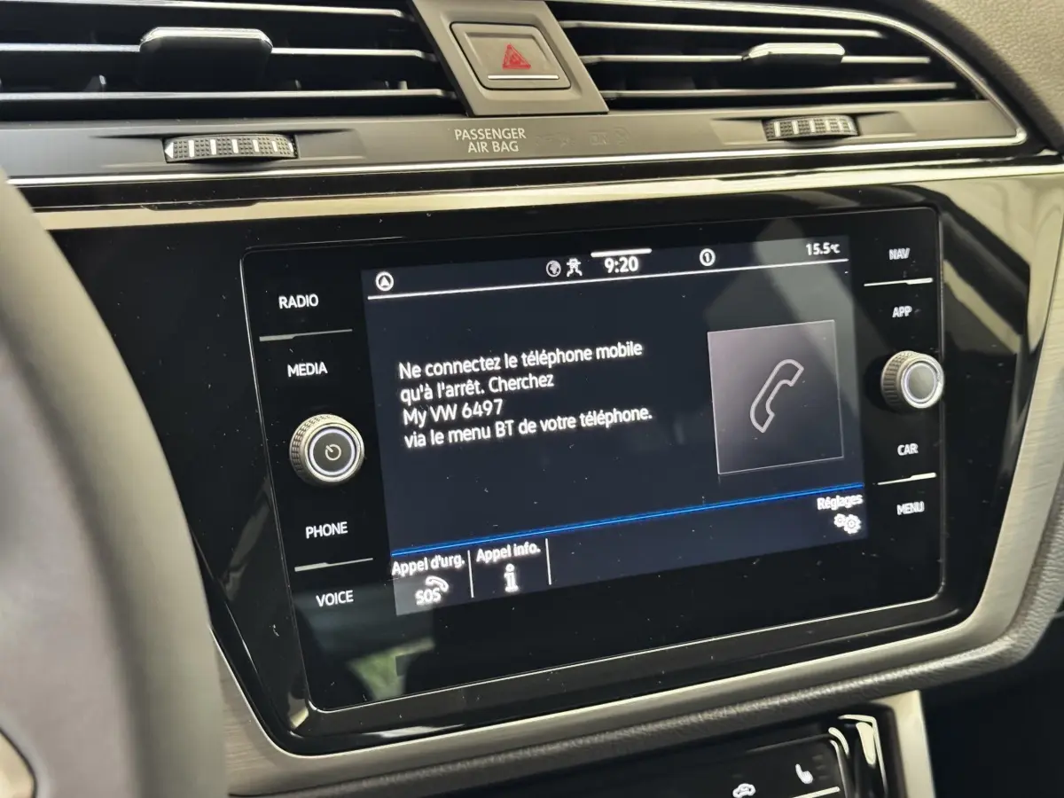 Gros plan sur l'écran tactile central noir du tableau de bord du Volkswagen Touran 2024 avec commandes autour.