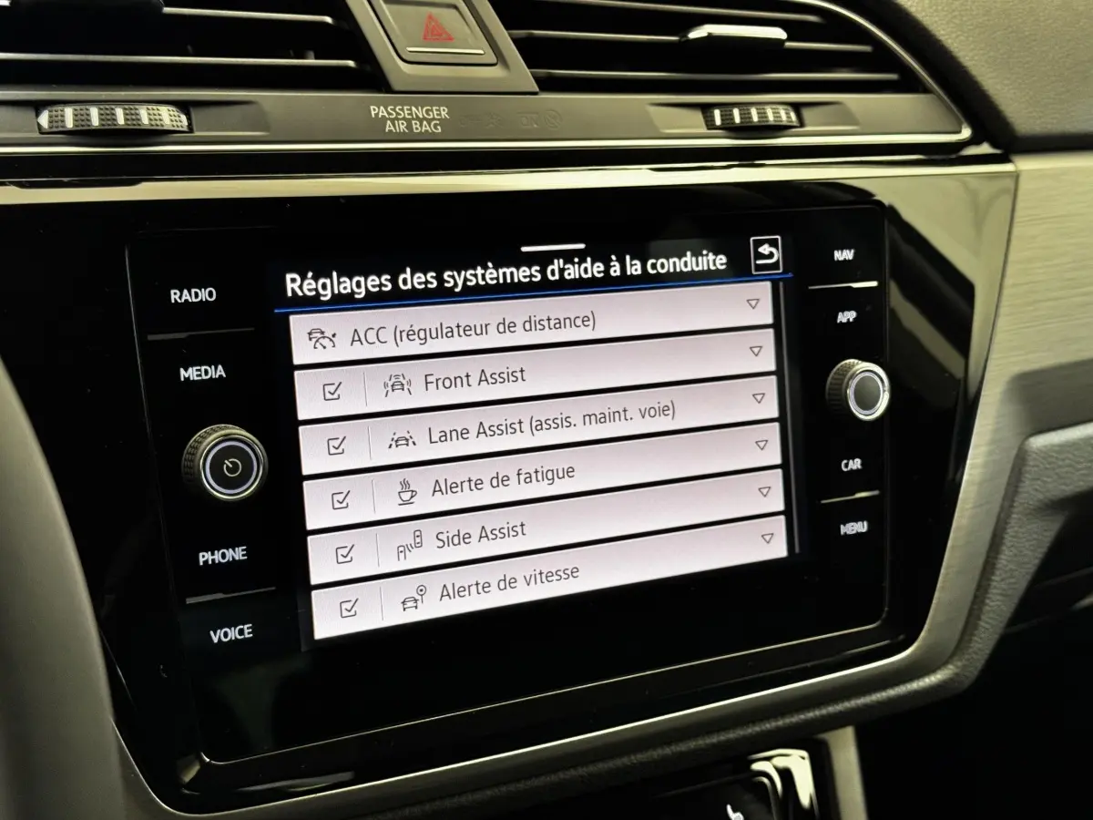 Écran tactile central du Volkswagen Touran 2024 affichant les réglages des aides à la conduite dans l'habitacle.