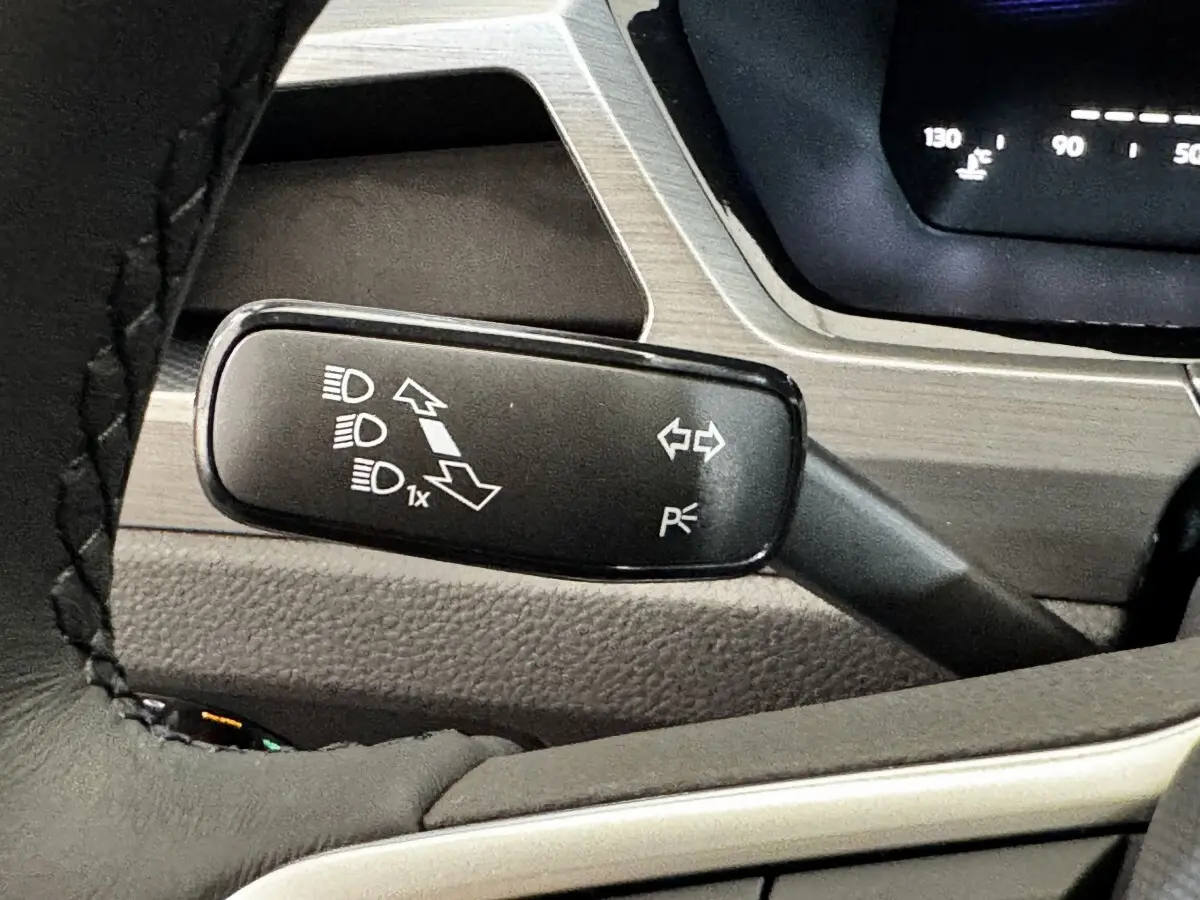 Gros plan sur la commande de clignotants et feux du Volkswagen Touran 2024, intérieur noir avec détails argentés.