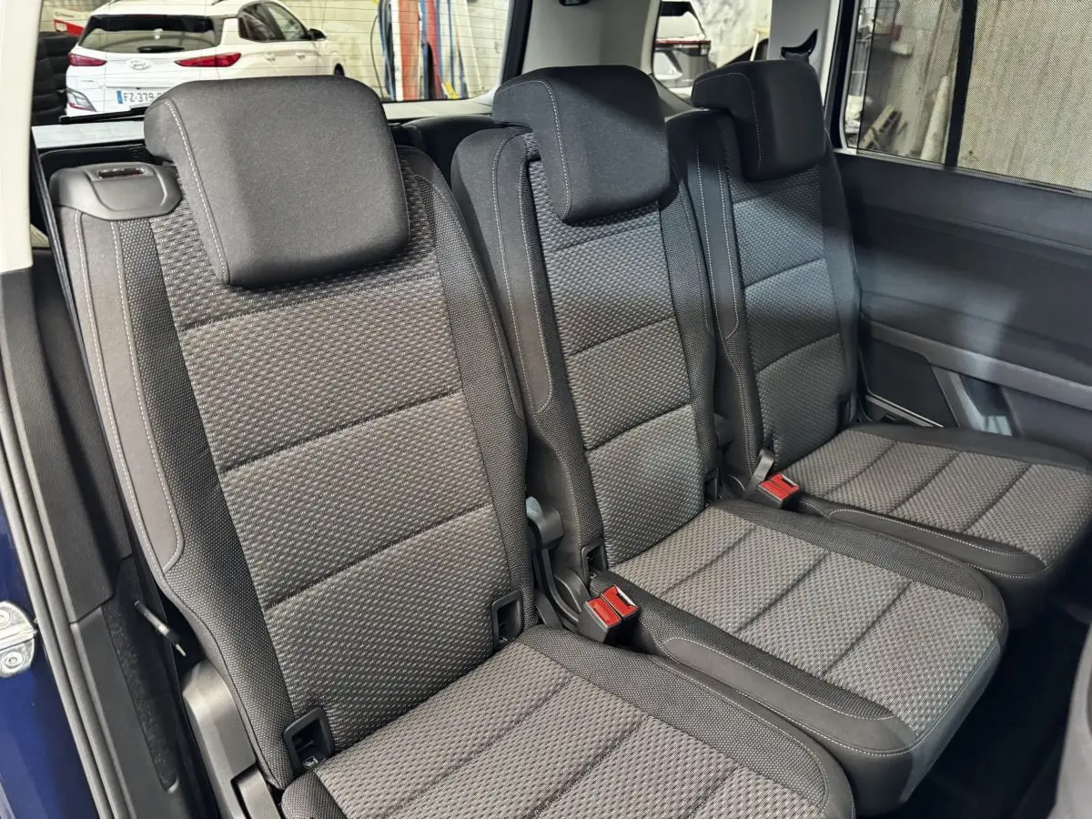 Vue rapprochée des trois sièges individuels arrière en tissu gris foncé du Volkswagen Touran 2024 bleu.