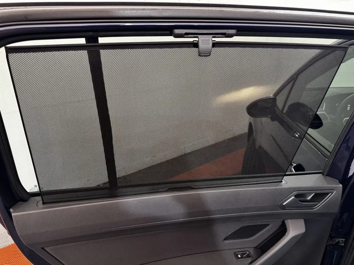 Store pare-soleil déployé sur la porte arrière côté gauche d’un Volkswagen Touran bleu 2024.