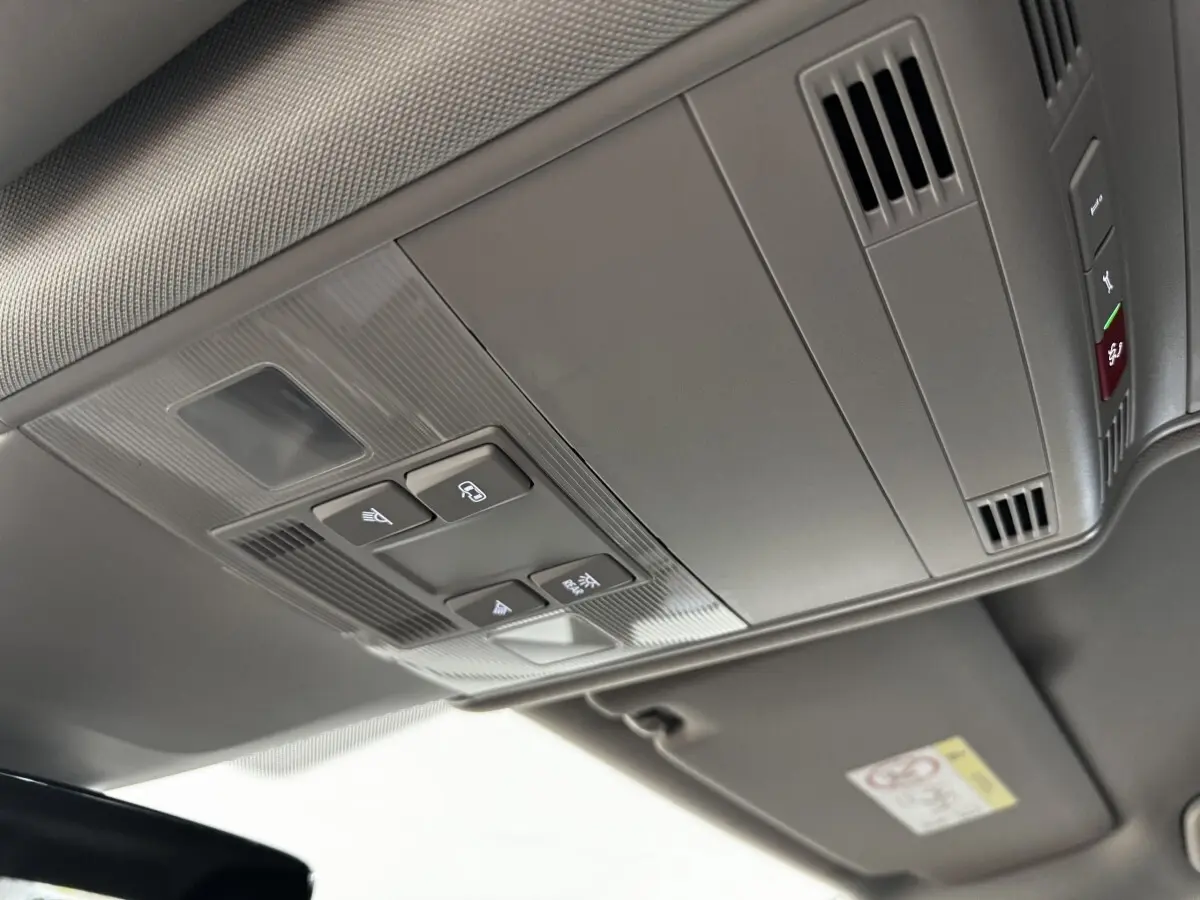 Vue en plongée sur le plafonnier gris du Volkswagen Touran 2024 avec commandes d’éclairage et ventilation intégrées.