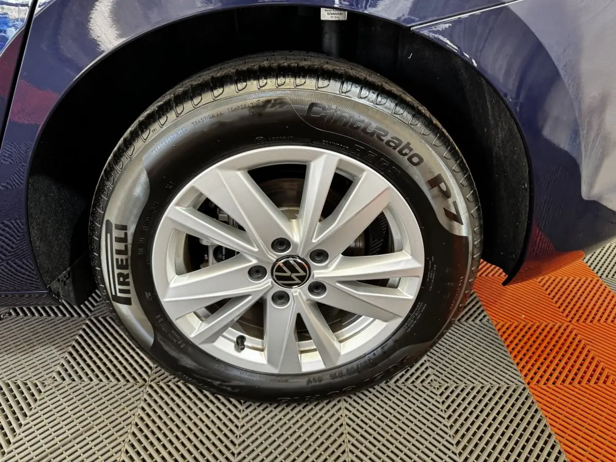 Gros plan sur la roue avant droite bleu métallisé du Volkswagen Touran 2024 avec jante alliage et pneu Pirelli Cinturato P7.