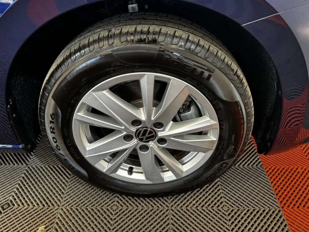 Gros plan sur la roue avant droite du Volkswagen Touran bleu 2024, avec jante alliage argentée et pneu Pirelli.