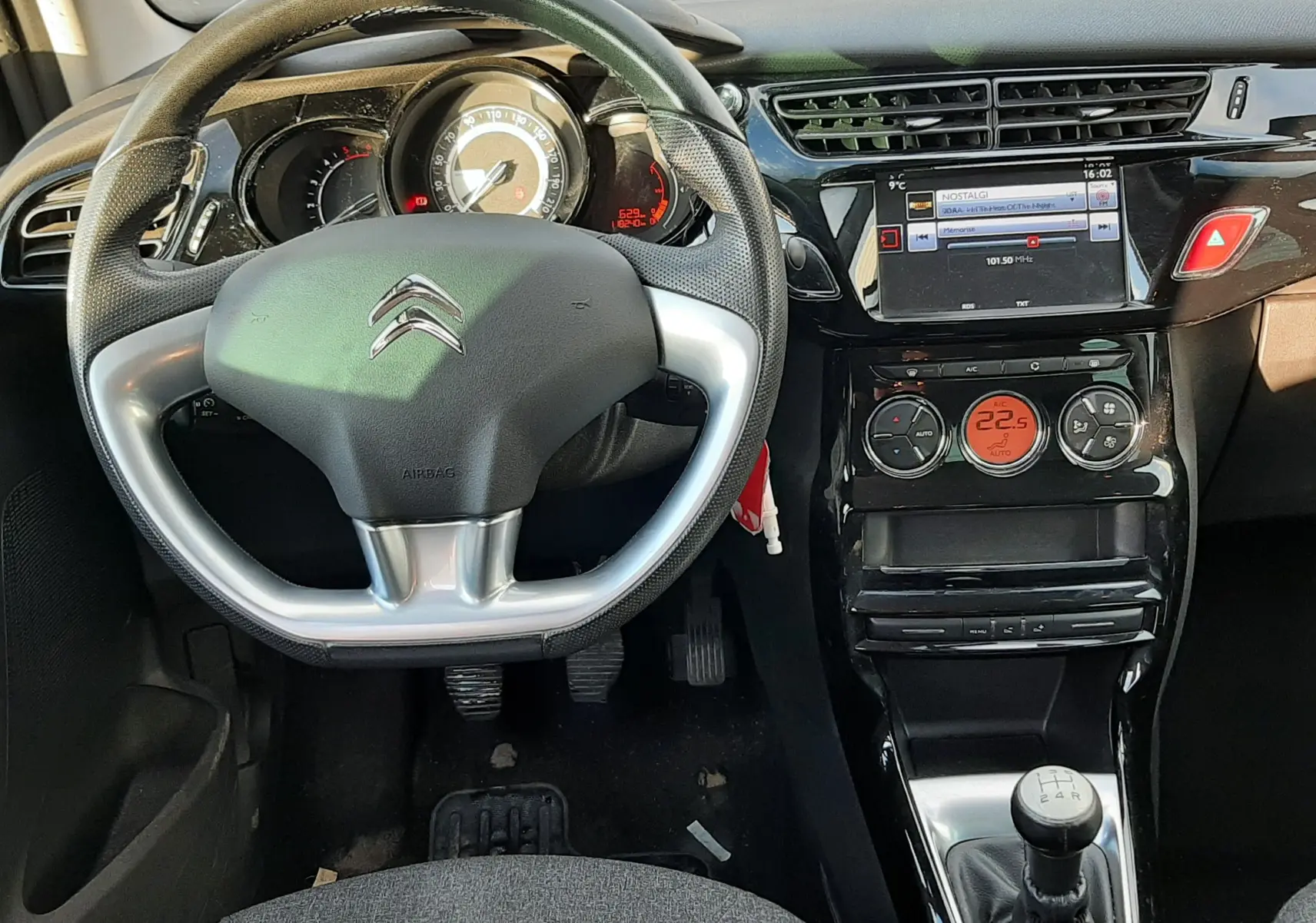 Vue intérieure du tableau de bord et volant Citroën C3 BlueHDi 75 Exclusive 2016 avec console centrale brillante et levier de vitesse manuel.