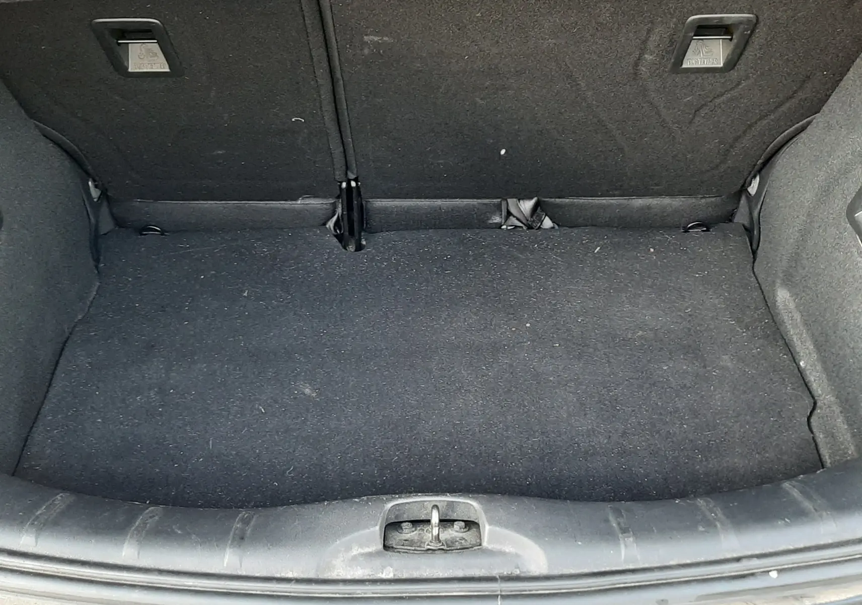 Coffre ouvert vu de l'arrière d'une Citroën C3 noire, montrant un espace de chargement propre et vide.